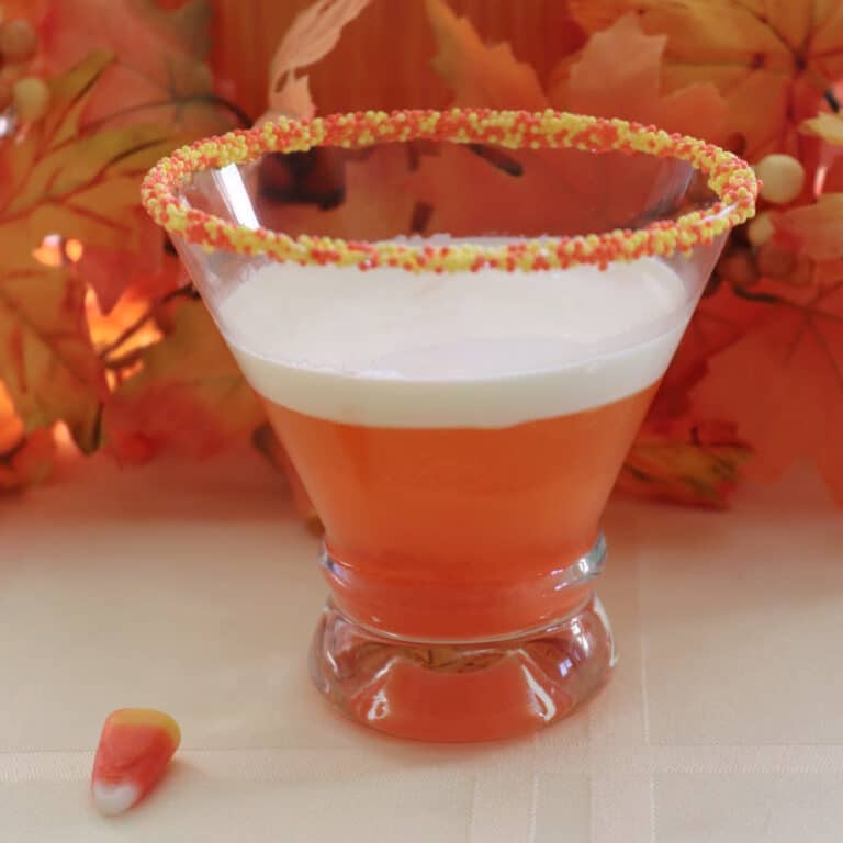 A candy corn martini on a yellow table cloth.