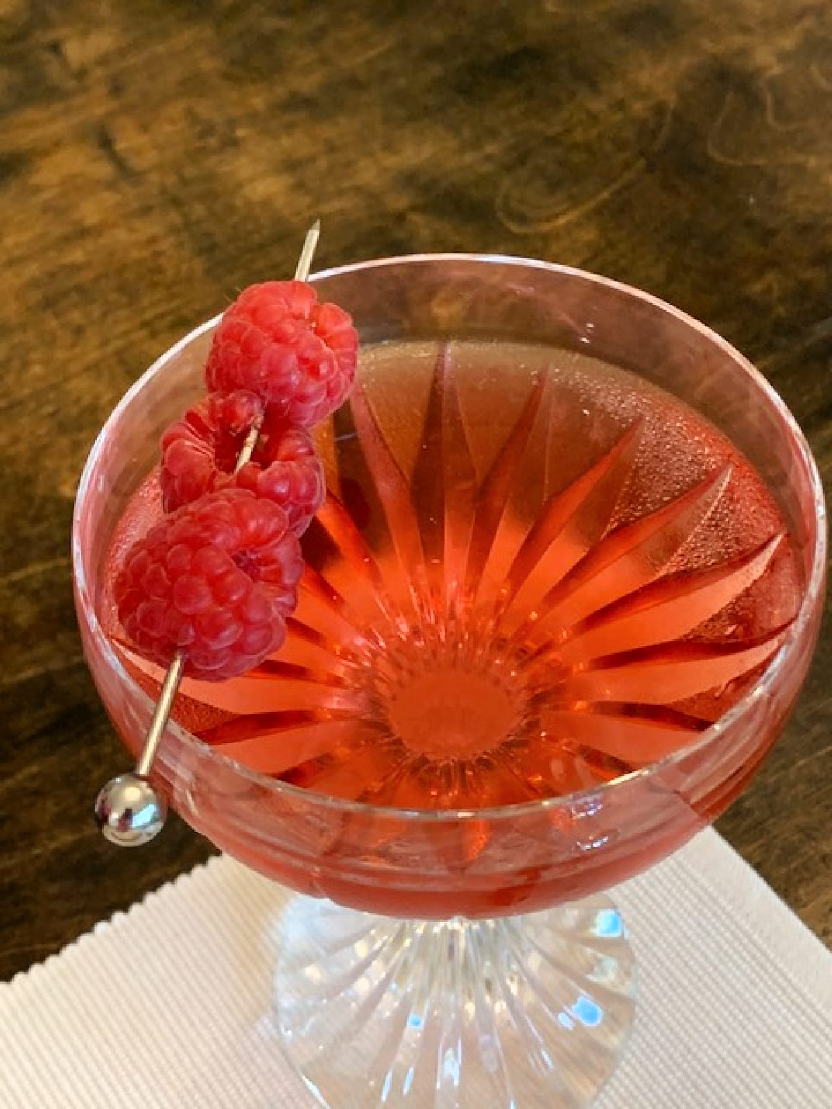 Overhead view of raspberry vodka cocktail garnished with fresh raspberries.