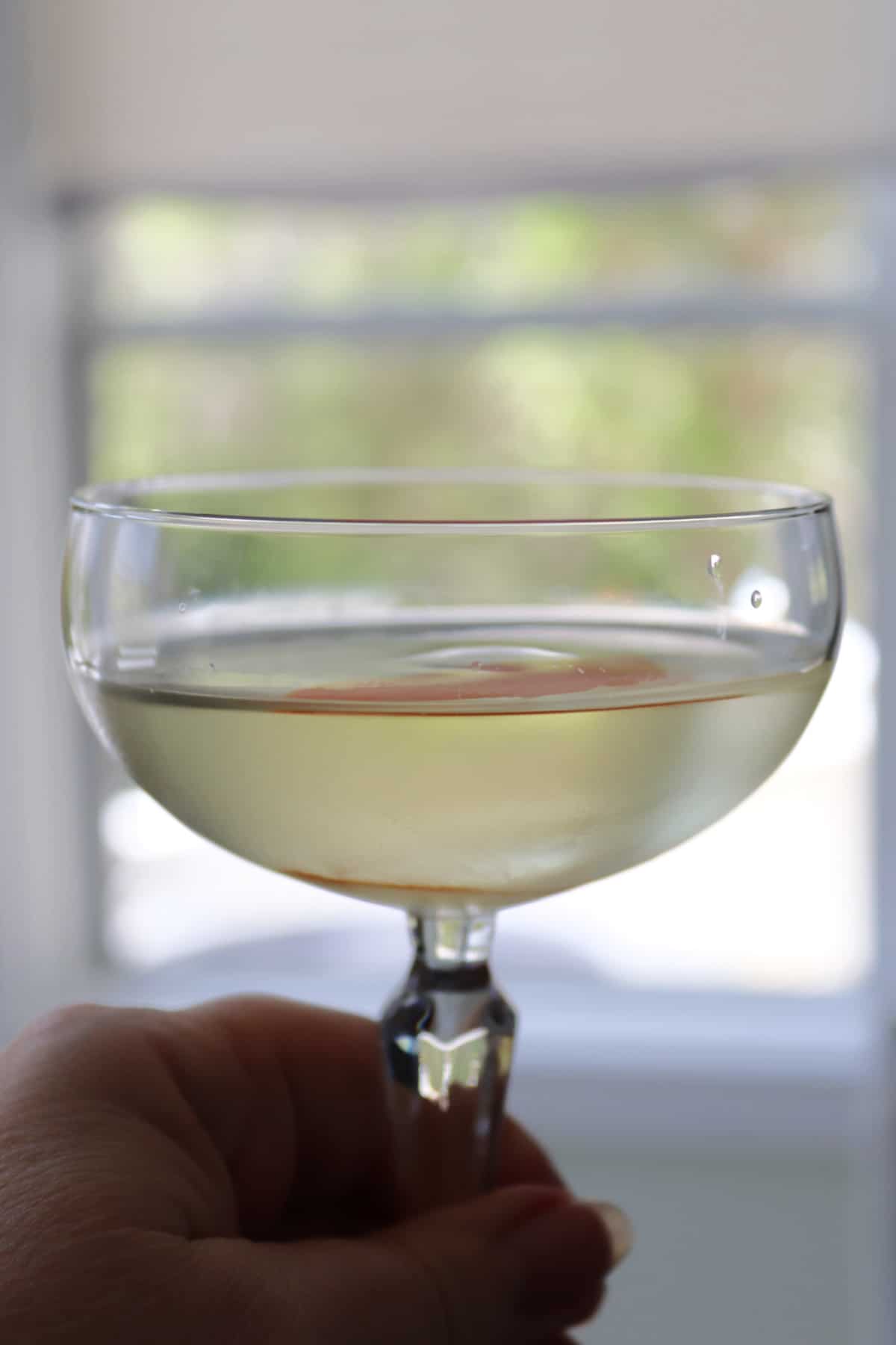 A coupe cocktail glass being held.