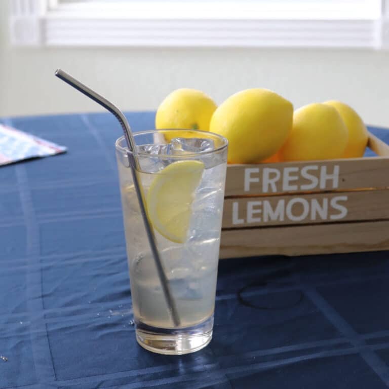 Tequila lemonade cocktail on a table with a small crate of lemons behind it.